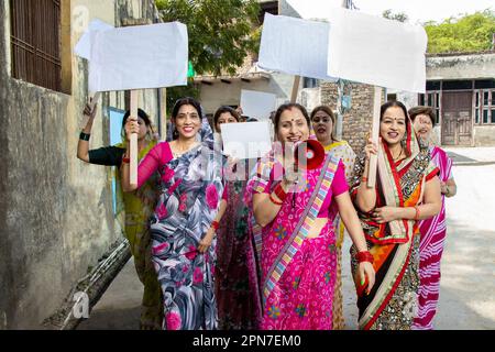 Groupe de femmes indiennes traditionnelles portant une étiquette en carton vierge pour protester contre la chute du mégaphone. Militante protestant avec le mégaphone pendant un Banque D'Images