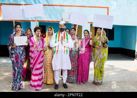 Homme politique indien debout faisant du namaste avec un groupe de femmes traditionnelles tenant une carte vierge. Concept d'élection et de vote. Banque D'Images