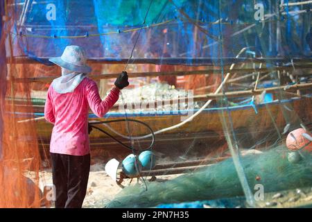 Femme nettoyant filet de pêche, après être de retour de la pêche dans la province de Phatthalung-Thaïlande Banque D'Images