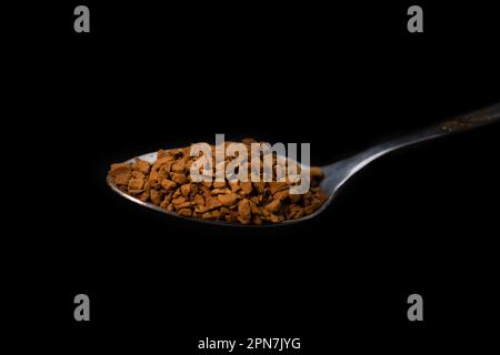 Gros plan de café granulé instantané dans une cuillère à café sur fond noir, photographie macro Banque D'Images