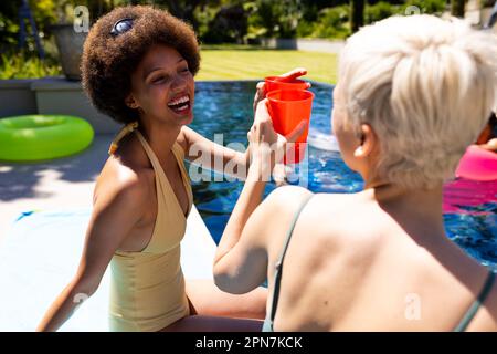 Joyeux amis de diverses femmes ayant la fête de la piscine, faire un toast et sourire dans le jardin Banque D'Images