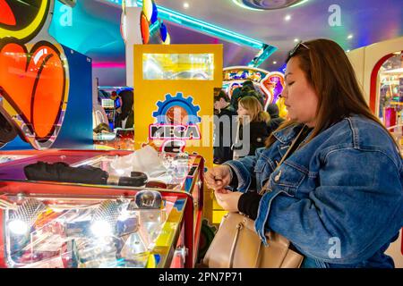 Une dame se concentrant, jouant un penny Falls machine dans une arcade à Bournemouth, Royaume-Uni Banque D'Images