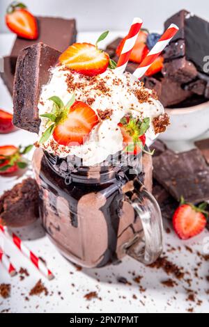 Milk-Shake au chocolat double. Cocktail délirant au goût de brownie, sauce au chocolat, garniture à la crème fouettée et fraise fraîche, swe sucré d'été chargé Banque D'Images