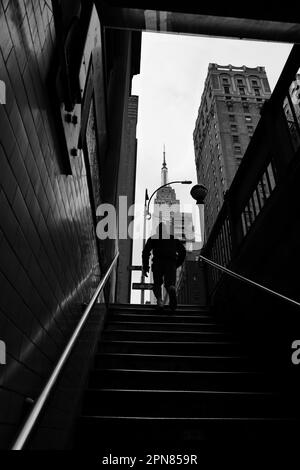 Homme en train de monter des marches de métro vers l'Empire State Building à New York Banque D'Images