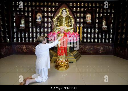 Temple bouddhiste de Phat Quang. Siddhartha Gautama, le Bouddha Shakyamuni. Femme adoratrice s'agenouillant dans la prière et la méditation devant la statue de Bouddha. Banque D'Images