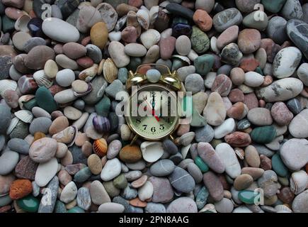 L'horloge vintage se trouve sur une petite coque et des galets de mer Banque D'Images