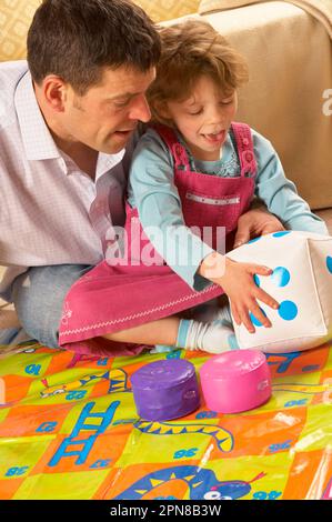 Père et jeune fille jouant avec un jeu de serpents et d'échelles d'intérieur surdimensionné Banque D'Images