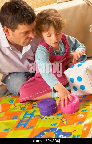 Père et jeune fille jouant avec un jeu de serpents et d'échelles d'intérieur surdimensionné Banque D'Images