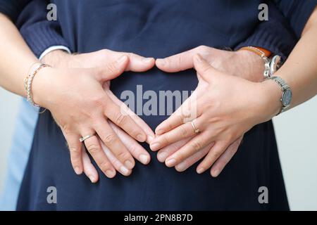 Femme enceinte et son homme en forme de coeur formant avec leurs mains. Banque D'Images