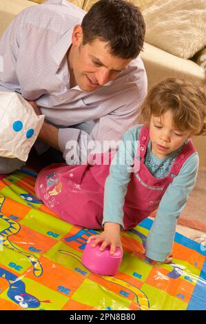 Père et jeune fille jouant avec un jeu de serpents et d'échelles d'intérieur surdimensionné Banque D'Images