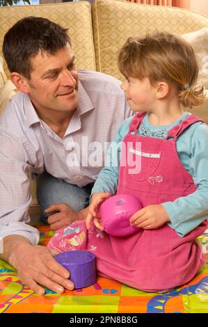 Père et jeune fille jouant avec un jeu de serpents et d'échelles d'intérieur surdimensionné Banque D'Images