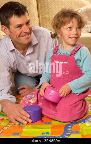 Père et jeune fille jouant avec un jeu de serpents et d'échelles d'intérieur surdimensionné Banque D'Images