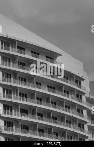 Une image architecturale en noir et blanc d'un grand complexe d'appartements avec plusieurs balcons Banque D'Images