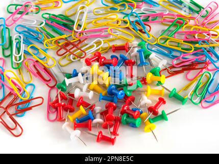 Trombones colorés et boutons de papeterie isolés sur fond blanc. Vue de dessus Banque D'Images