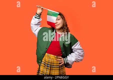 Fille portant dans la tenue d'école et tient le petit drapeau national de l'Italie. Banque D'Images