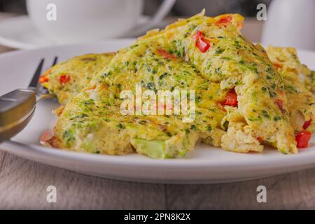 Le brocoli et l'omelette aux oignons ont été abattus en gros plan sur une assiette blanche. Banque D'Images