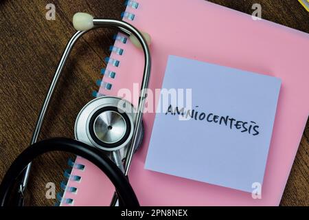 Concept d'Amniocentèse écrire sur des notes adhésives avec stéthoscope isolé sur une table en bois. Banque D'Images