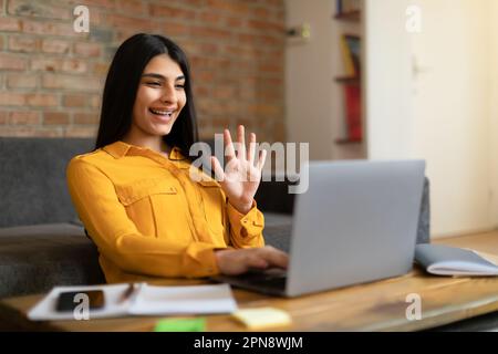 Adolescente mexicaine excitée ayant des appels vidéo et se faisant passer les mains à la webcamera ordinateur portable, étudiant en ligne de la maison Banque D'Images