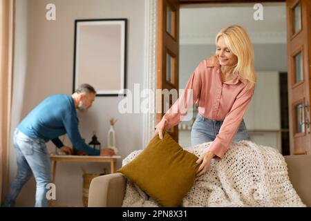 Chambre de nettoyage de couple mature faisant des travaux de maison ensemble à la maison Banque D'Images