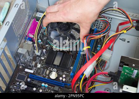 La personne répare la carte mère de l'ordinateur, en démontant le processeur Banque D'Images