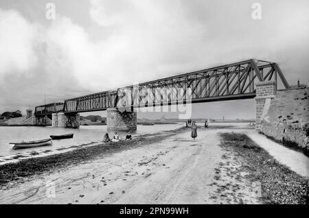 Vue de la fin du siècle 19th sur le pont Midland et Great Western Railway au-dessus de la rivière Corrib dans la ville de Galway, en Irlande. Au-delà de la rive de la rivière, on peut voir une tour ronde éloignée et une cabane de pêche appartenant à une famille locale. Banque D'Images