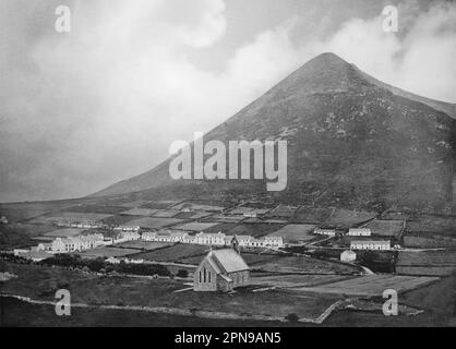 Vue de la fin du 19th siècle sur le village de Dugort avec l'église épiscopale en premier plan et la montagne de Slievemore qui s'élève derrière. Sur la côte nord de l'île d'Achill, la plus grande des îles irlandaises se trouve au large de la côte ouest de l'Irlande dans le comté de Mayo. Banque D'Images