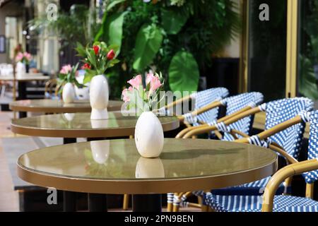 Street café dans la ville avec des tables vides à l'extérieur. Fleurs dans des vases sur des tables rondes par beau temps Banque D'Images