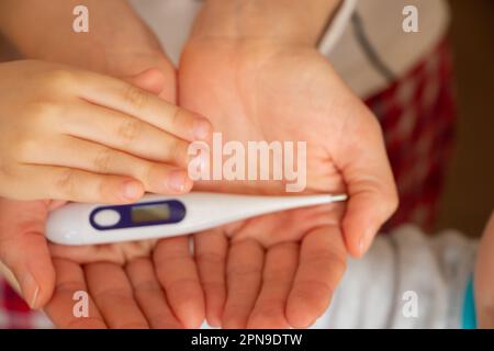 les mains des femmes tiennent un thermomètre électronique Banque D'Images