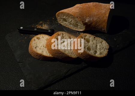 Tranches de pain avec des miettes sur un fond de tableau noir. Vue avant. Nourriture maison du monde. Banque D'Images