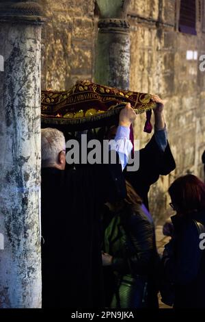 Les croyants viennent à l'église byzantine de Panagia Kapnikarea pendant l'Epitaph (Vendredi Saint), passant sous un tapis qui représente l'Epitaph. Banque D'Images