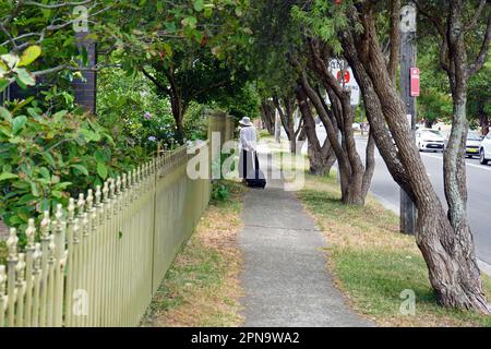 Une femme marchant dans un trottoir à côté de W Botany St à Sydney. Banque D'Images