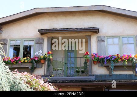 Balcon en fer forgé avec deux chaises et fleurs colorées dans le charmant village de bord de mer de Carmel-by-the-Sea, CA. Banque D'Images