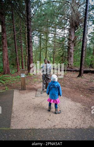 Astoria, Oregon, États-Unis. Lewis et Clark National Historical Park, jeune fille debout devant 'Stagawea and Baby' par Jim Demetro. Banque D'Images