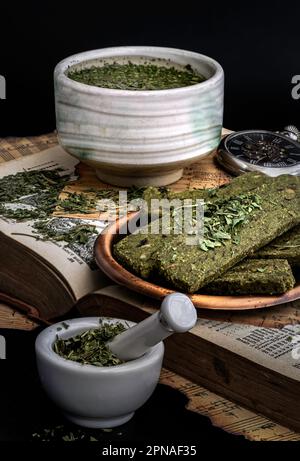 Dégustez une tasse de thé à l'hemp chaud (thé aux herbes CBD) servi avec le Cannabis snack Stick maison, qui sont sur l'Old Song Book avec le dos sombre Banque D'Images