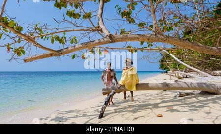 Un couple d'hommes et de femmes sur la plage de l'île de Koh Kradan en Thaïlande, des hommes et des femmes se détendant sur la plage avec une tourte de couleur océan sur une journée ensoleillée en vacances Banque D'Images