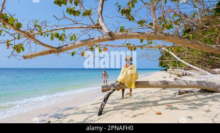 Un couple d'hommes et de femmes sur la plage de l'île de Koh Kradan en Thaïlande, des hommes et des femmes se détendant sur la plage avec une tourte de couleur océan sur une journée ensoleillée en vacances Banque D'Images