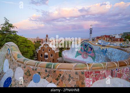 Bancs avec mosaïque colorée, bâtiment d'entrée à l'arrière, Casa de la Guardia, Pabellon de Porteria, vue sur la ville dans la lumière du soir Banque D'Images