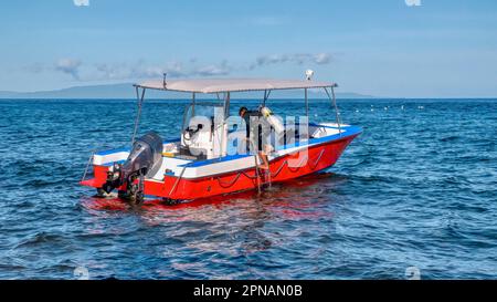 Un boatman non identifié de station charge des réservoirs d'air dans le bateau en préparation pour la plongée sous-marine de groupe suivante, aux Philippines. Banque D'Images