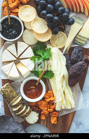 Plateau de fromages avec fruits et craquelins, gros plan. Plats de fête, plat, hors-d'œuvre européens. Banque D'Images