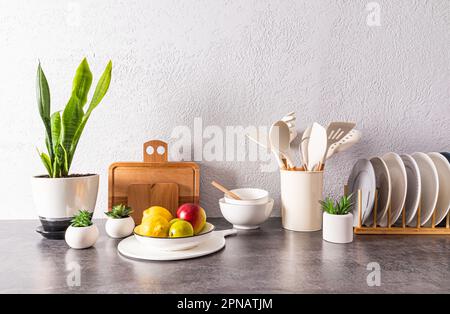 un ensemble de plats divers, outils, un bol de fruits sur un comptoir en pierre face d'un mur texturé gris. espace pour le texte. encore la vie Banque D'Images