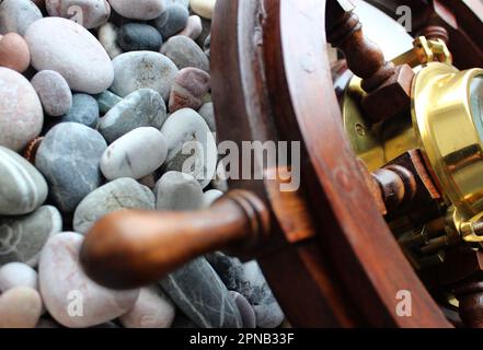 Partie de Voilier Helm avec Сopper Edging Boussole à l'intérieur sur Un fond de Round Sea Rocks Banque D'Images