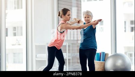 Rester en forme contribue à prévenir les maladies et les maladies chroniques. un instructeur de fitness aidant une femme âgée pendant un cours de yoga. Banque D'Images