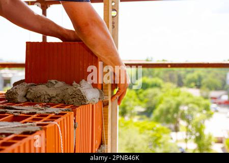 Le constructeur utilise un niveau à bulle pour vérifier le nouveau mur de briques rouges fait de blocs rouges, couche de briques. Bord de l'édifice en construction Banque D'Images