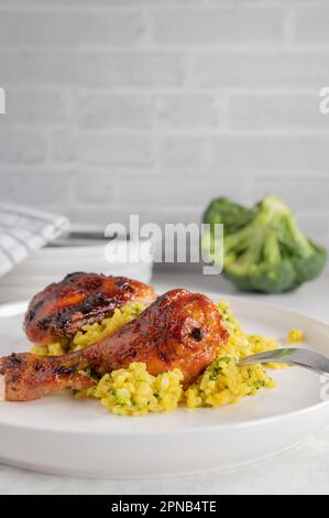 Pilons de poulet cuits au four et glacés avec curry, riz brun brocoli sur une assiette Banque D'Images