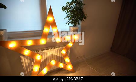 Gros plan d'une étoile lumineuse électrique avec des lumières jaunes chaudes. Décorations d'éclairage étoiles à la maison, Noël et fête du nouvel an à la maison Banque D'Images