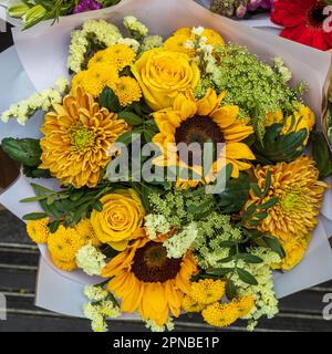 Chrysanthèmes jaunes, roses, tournesols et gerberas à l'eucalyptus dans un bouquet de tons jaunes Banque D'Images