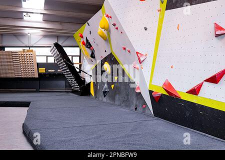 Vue en grand angle de divers murs de blocs avec des poignées de couleur dans la salle de gym pour l'entraînement et la pratique de grimpeurs frais alpinistes avec floo amorti Banque D'Images