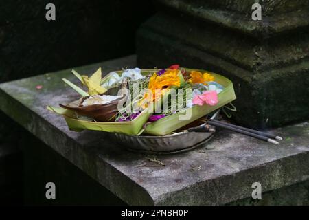 Canang sari, contenant en bambou tissé avec riz, fleurs, encens, bonbons et fruits. C'est une offre aux Dieux, comme un geste de gratitude à Bali Banque D'Images