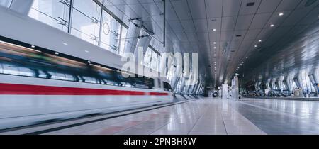 Un train de voyageurs à grande vitesse se précipitant dans un terminal d'aéroport très animé en début de matinée Banque D'Images