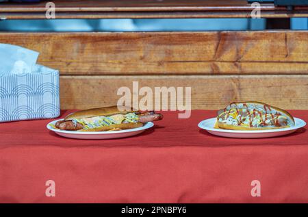 Hot Dogs avec ketchup et moutarde sur des assiettes en plastique blanc à vendre. Banque D'Images